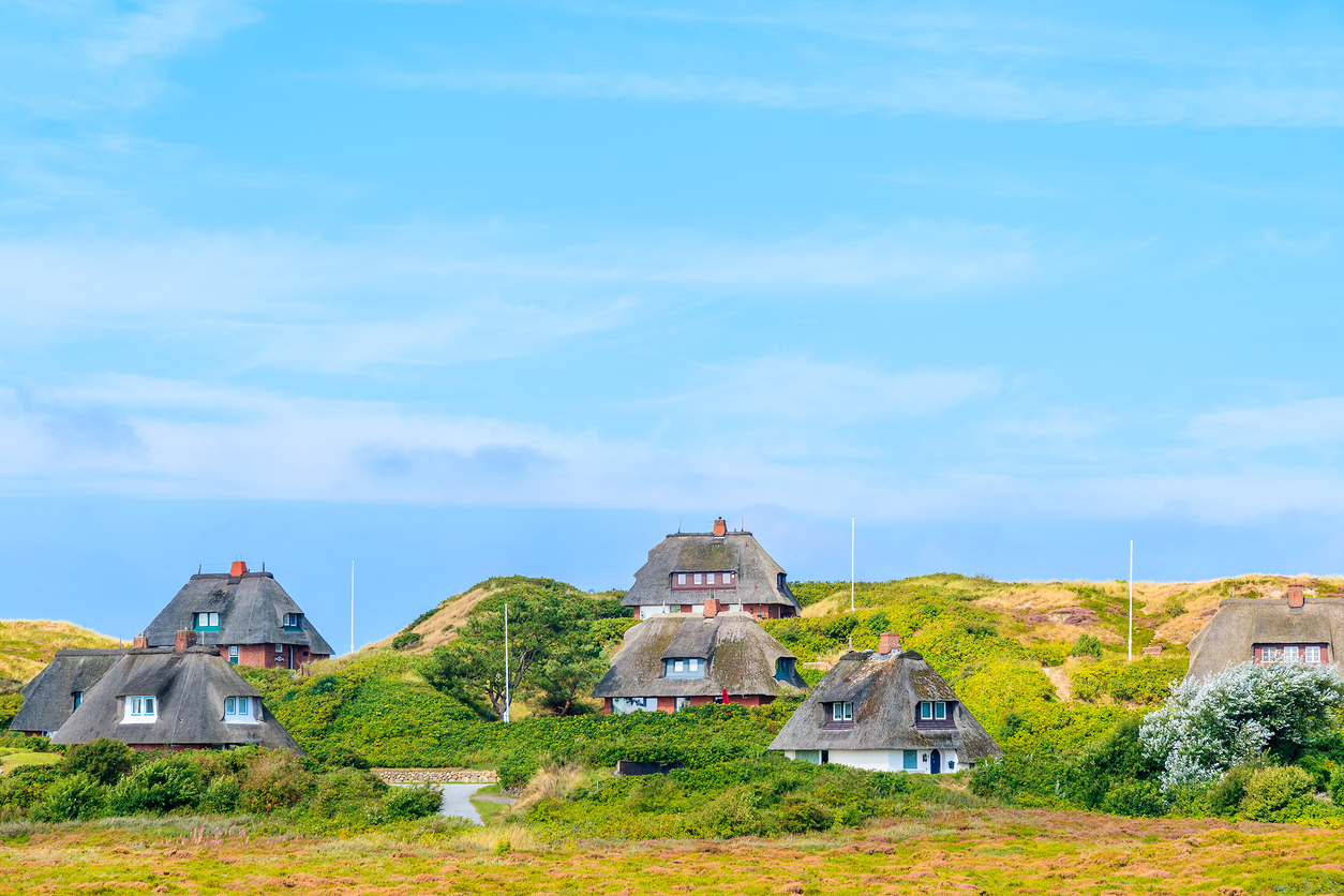 Maisons typiques avec toits de paille sur les dunes de sable dans le village de Kampen, île de Sylt, Allemagne. © iStock / pkazmierczak