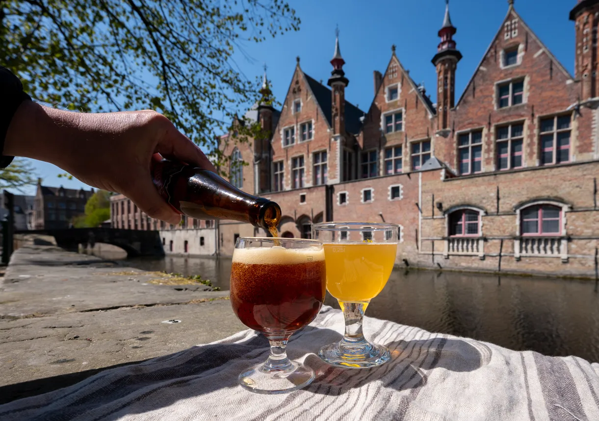 Dégustation de bière belge sur une terrasse avec vue sur les maisons médiévales et les canaux de Bruges en Flandre, Belgique © iStock / barmalini