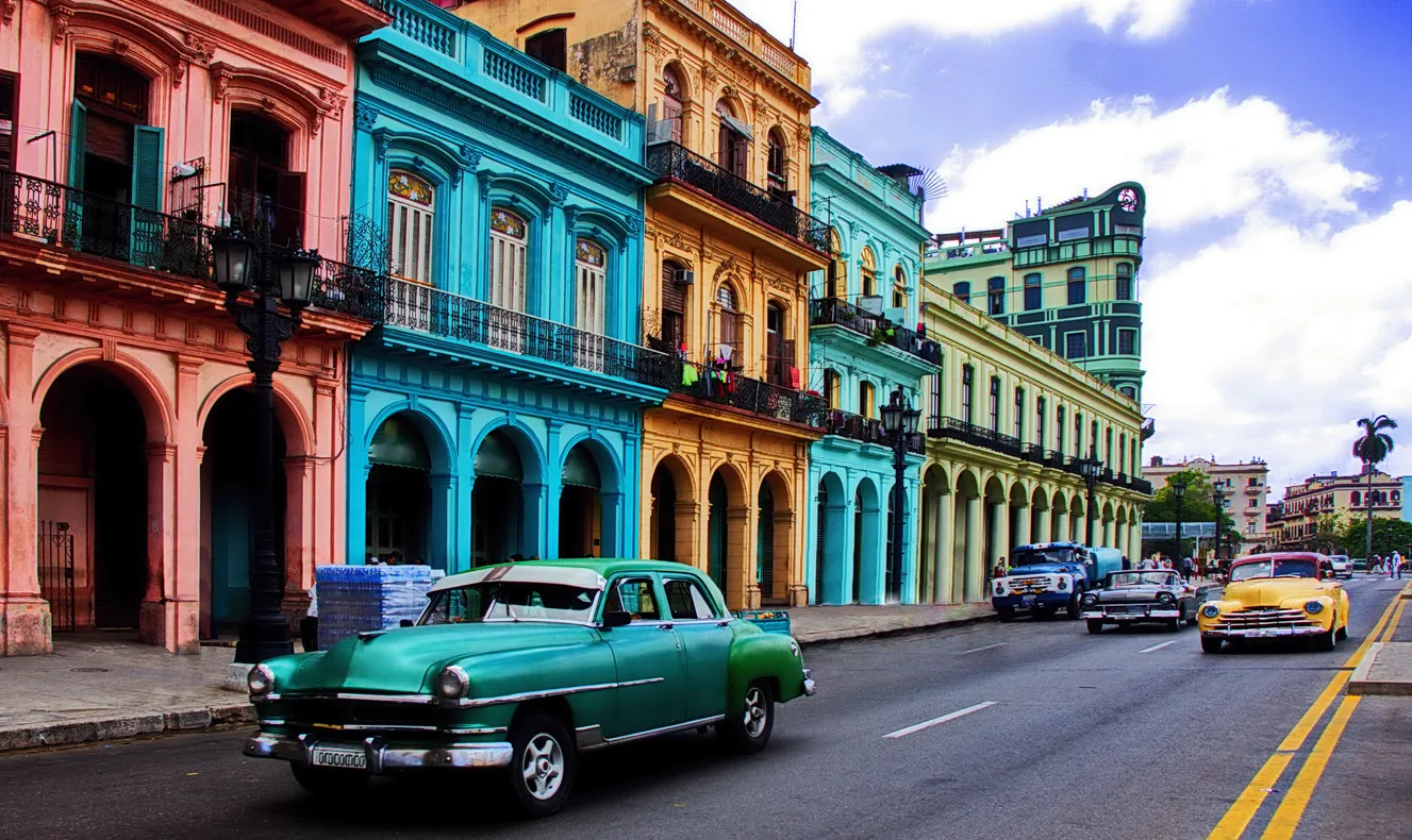 Scène de rue avec bâtiments coloniaux colorés et  vieilles voitures à La Havane, la capitale de Cuba© iStock / MWayOut